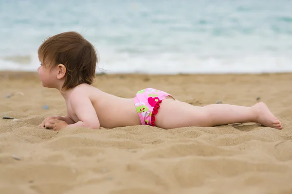 Menina da criança deitado na praia de areia — Fotografia de Stock