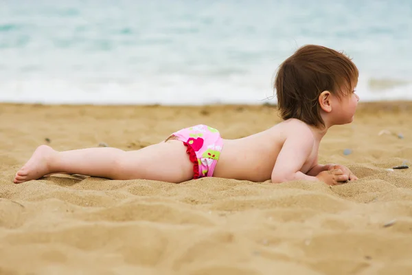 Niña pequeña acostada en la playa de arena — Foto de Stock