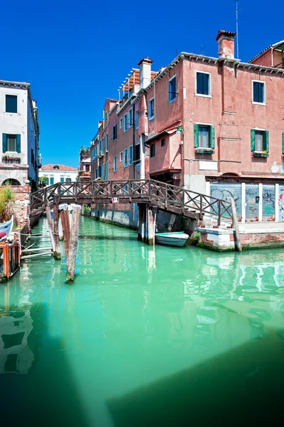 Farbiger venezianischer Kanal mit Brücke und Häusern, die im Wasser stehen, i — Stockfoto
