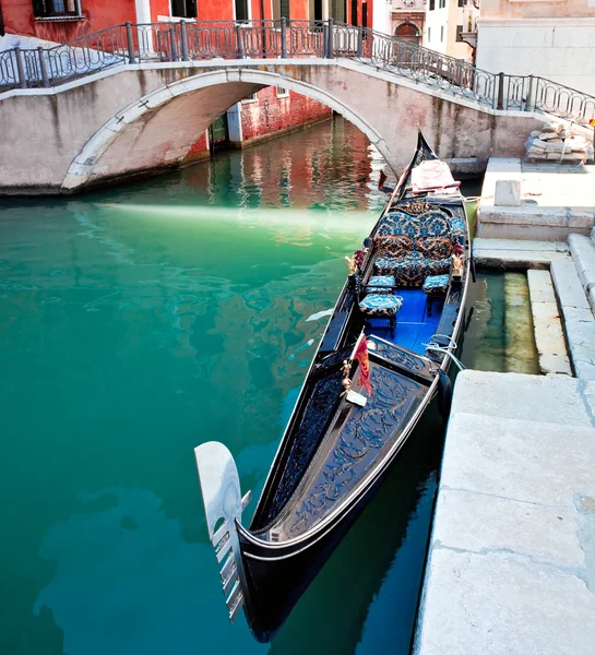 Gondola on Venice canal with bridge and houses standing in water — Stock Photo, Image