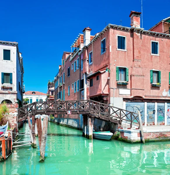 Farbiger venezianischer Kanal mit Brücke und Häusern, die im Wasser stehen, i Stockbild