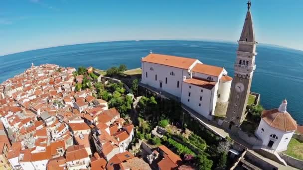 Vuelo y despegue sobre la ciudad vieja Piran, vista panorámica aérea con iglesia, casas antiguas y el mar . — Vídeo de stock