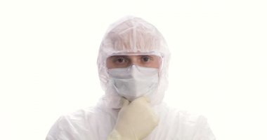 Koruyucu giysiler içinde bir doktor ya da tıbbi personel portresi. Adam üzgün bir şekilde başını sallıyor. Yakın çekim..