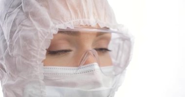 Koruyucu takım elbiseli, maskeli ve gözlüklü ünlü bir doktorun yüzü. O yorgun görünüyor. Çok çalıştıktan sonra enfeksiyoncu doktor.