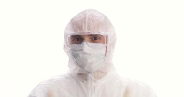 Koruyucu giysiler içinde bir doktor ya da tıbbi personel portresi. Memnuniyetle baş parmağını kaldırır. Gülümsüyor. Yakın çekim..