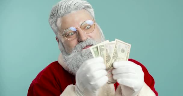 Legrační Stylový Santa Claus na modrém pozadí pózování s penězi dolarů. Finance, peníze, bankovky. Detailní záběr — Stock video