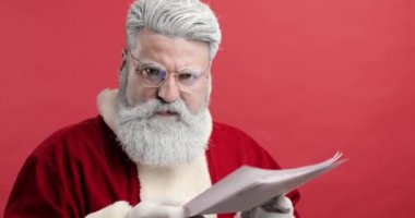 Hayal kırıklığına uğramış bir Noel Baba 'nın portresi kameraya bakıyor ve çocuklardan gelen mektupları okuyor. Öfkeli, hoşnutsuz, agresif, mavi arka planda Noel Baba.