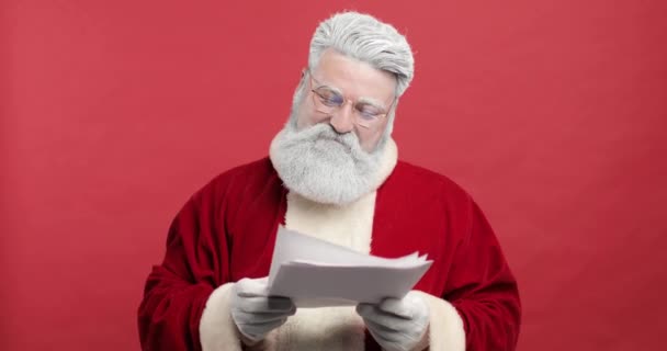 Moș Crăciun fericit, Sfânta Nicholas Reading Wishes Letter, Verificarea listei cadou de vise pentru copii. El este fericit, mulţumit şi fericit. fundal roșu — Videoclip de stoc
