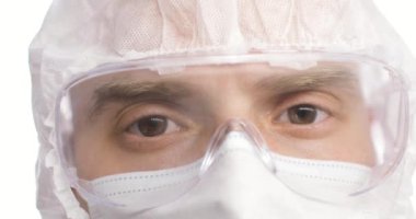 Genç erkek doktorun yüzü. Güvenlik gözlüklü gözlerinizi kapatın. Salgın sırasında koruyucu gözlük takan portre doktoru.