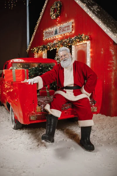 Πορτρέτο του Αϊ Βασίλη με αυτοκίνητο, πολλά δώρα στο πίσω μέρος. Προετοιμασία δώρων για τον εορτασμό των Χριστουγέννων και της Πρωτοχρονιάς — Φωτογραφία Αρχείου