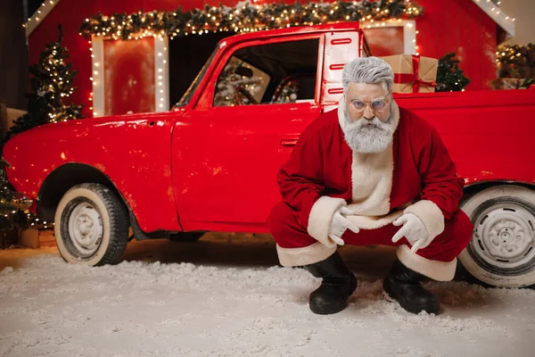 차 근처에 선물을 가지고 있는 멋지고 멋진 산타클로스의 모습. 크리스마스와 새해를 위한 선물 준비 스톡 이미지