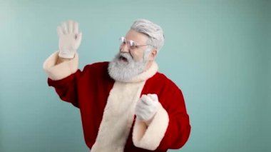 Neşeli Noel Baba konfetileri havaya uçuruyor. Seviniyor, gülüyor. Mavi arkaplan