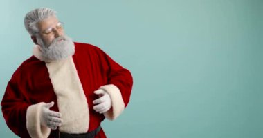 Modayı takip eden, neşeli, mutlu Noel Baba hipster dans ediyor, karnını okşuyor. mavi arkaplan