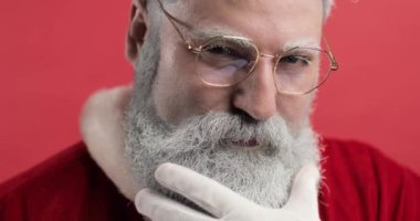 Şık, vahşi, güzel, Noel Baba 'nın modaya uygun portresi. Noel Baba kameraya bakar, gülümser ve sakalını eliyle düzeltir. Noel, yeni yıl