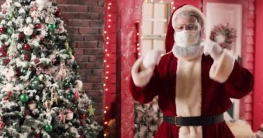 Noel Baba 'nın koruyucu bir maske takmış portresi ve güzel bir yeni yıl stüdyosunun ve Noel ağacının arka planında duran eldivenler. Noel Baba maskesini çıkarıp atıyor..
