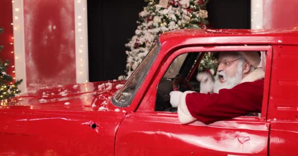 Angry aggressive Santa Claus shouting something from a red truck. Side view. In the background there is a Christmas tree. Celebrations and joyful people concept. — Stock Video