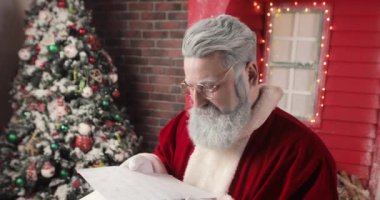 Mutlu bir Noel Baba 'nın portresi güzel bir Yeni Yıl süsleme stüdyosunda mutlu bir şekilde mektuplar okuyor..