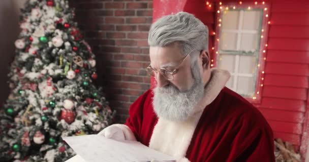 Mutlu bir Noel Baba 'nın portresi güzel bir Yeni Yıl süsleme stüdyosunda mutlu bir şekilde mektuplar okuyor.. — Stok video