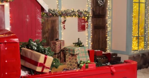 Santa Claus puts boxes of gifts to big red truck on Christmas Eve or New Year Eve. Beautiful New Years decorated studio. — Stock Video