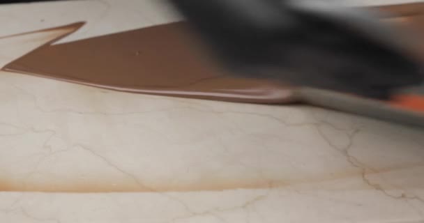 Smält choklad eller chokladkräm sprids över den vita marmorytan med en borste. — Stockvideo
