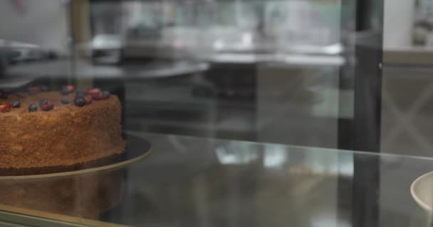 Domowej roboty tort jest umieszczony na gablocie z lodówką. Zbliżenie rąk. — Wideo stockowe