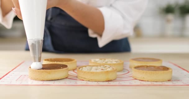 Pasticcere decora torta biscotto con crema da sacchetto di pasticceria, primo piano. Preparazione della torta a casa panificio con sacchetto tubazioni. — Video Stock