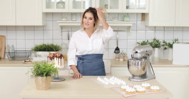 Retrato de una joven pastelera posando frente a una cámara de video después de cocinar postres en la cocina blanca. — Vídeos de Stock
