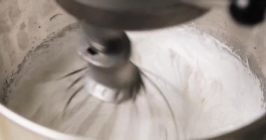 Şekerleme malzemeleri metal bir kasede karışıyor. Elektrikli mikser kullanarak tatlılar için krema yapıyorlar. Pişirme ve şekerleme adımları.