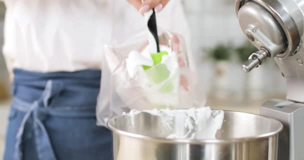 Makronen kochen. Großaufnahme der Hände von Köchen, die nach dem Rühren mit dem Mixer aus einer Metallschüssel in eine Packung weißen sanften Luftteig für Makronen überführen. — Stockvideo