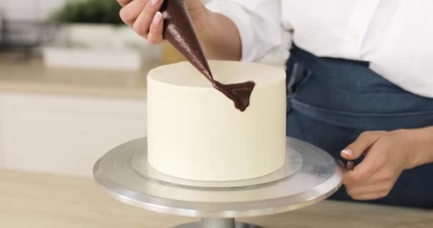 Білий торт, прикрашений випічкою з шоколадом. Обертається. Крупним планом руки . — стокове відео