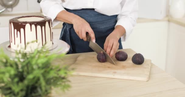 The pastry chef is cutting figs and decorating a cake or cheesecake. Close-up. — Stock video
