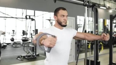 Spor salonunda çalışan profesyonel bir vücut geliştirme sporcusunun portresi. Ağırlık kaldırma. Adam makara ağırlığıyla göğüs egzersizi yapıyor..