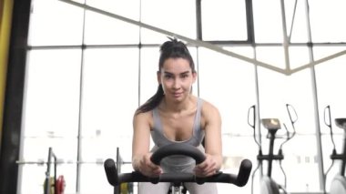 Spor salonunda egzersiz bisikletinde kardiyo yapan güzel bir esmer kadının portresi..
