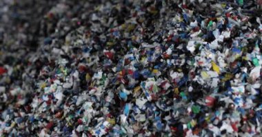Parçalanmış çok renkli plastikler. Yakın plan. Atık geri dönüşüm aşaması. Kamera hareket ediyor..