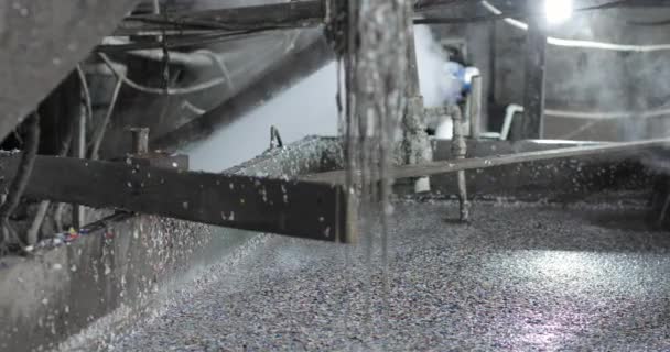Recycling plastic by dissolving in a metal reactor using hot steam.A large amount of crushed plastic is falling from the chopper into a special liquid. — Video Stock