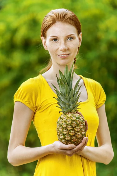 Ung kvinna i gul blus med ananas — Stockfoto