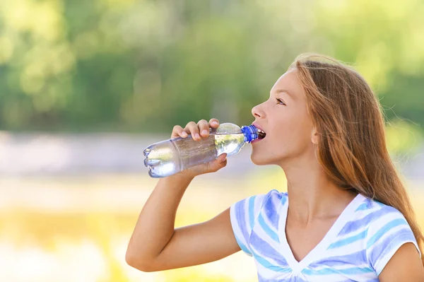 Teenage girl drinks water from bottle — Stock Photo, Image