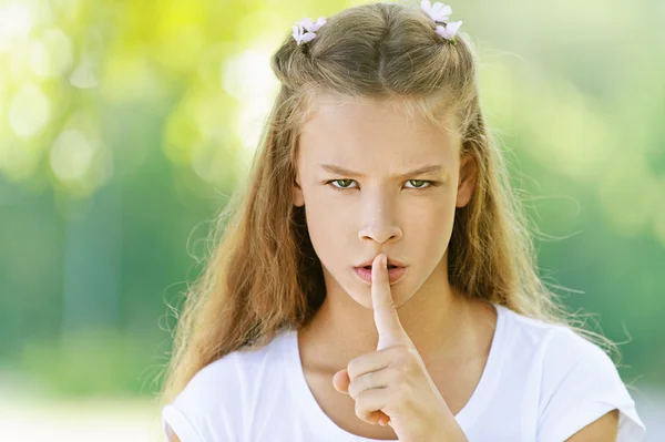 Tienermeisje opgeheven wijsvinger aan haar lippen — Stockfoto