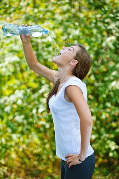 Young woman drinks water from bottle — Stock Photo, Image