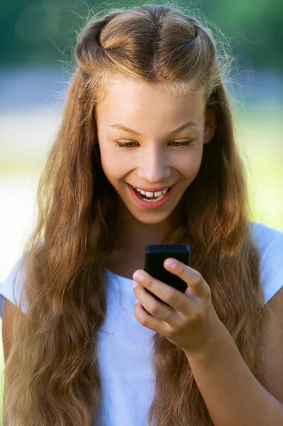 Девочка-подросток читает смешные сообщения по телефону — стоковое фото