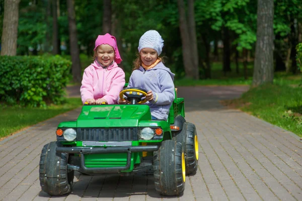 Смешные сестры ездят в маленькой зеленой игрушечной машине — стоковое фото