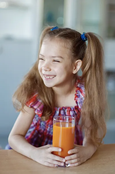 Liten flicka, som sitter på bordet och dricka juice — Stockfoto