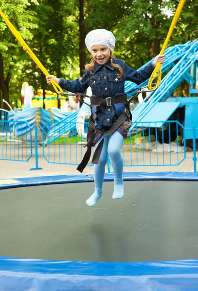 Happy little girl jumping on trampoline — Stock Photo, Image