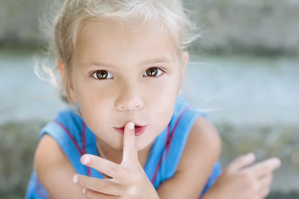 Ittle girl puts her finger to mouth — Stock Photo, Image