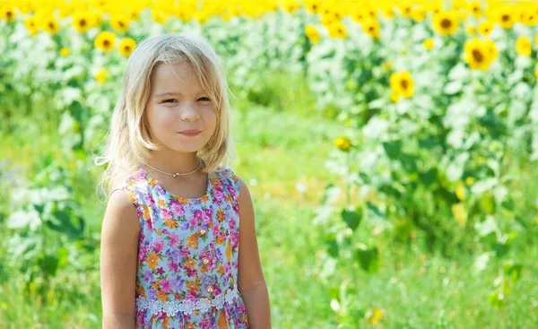 Vacker leende liten flicka på solros fält — Stockfoto