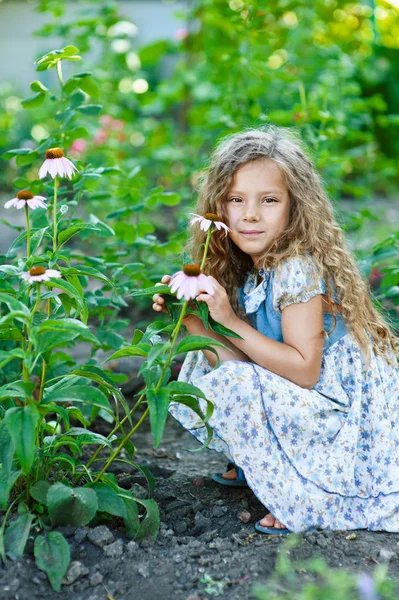 Niña pequeña con el pelo rizado sobre el crecimiento de flores — Foto de Stock