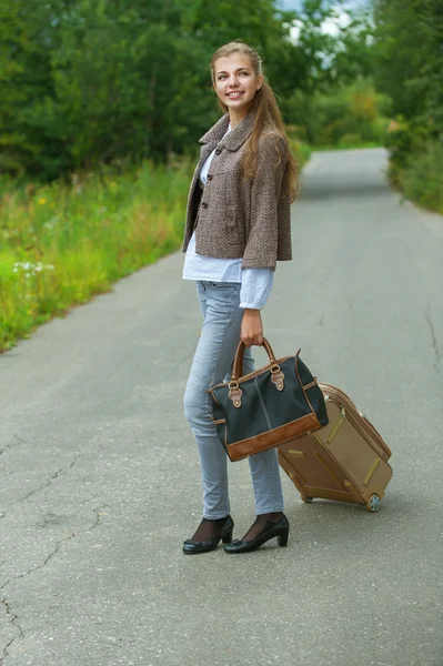 Lachende mooie jonge vrouw met weg koffer — Stockfoto