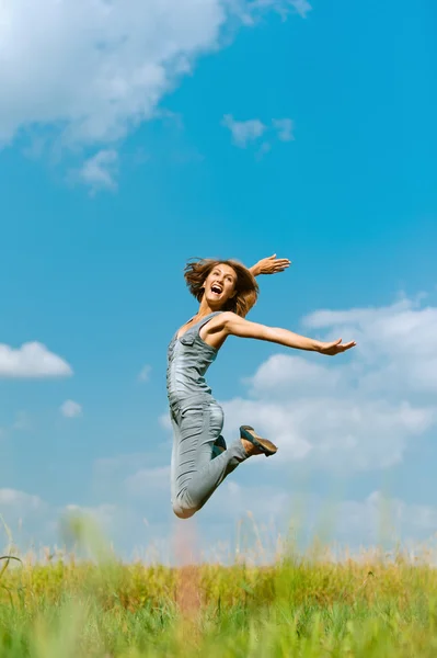 Lächelnde junge Frau springt Stockbild