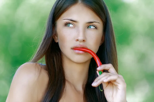 Donkerharige nadenkend vrouw in zijn mond paprika — Stockfoto