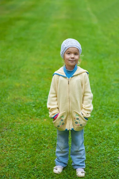 Little girl standing on green lawn — Stock Photo, Image